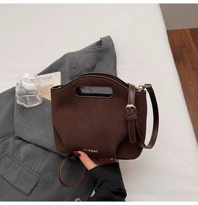 Detail of dark brown matte bucket bag with golden MOEDNT logo and suede texture