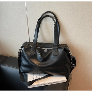 Close-up of matte black leather travel tote bag with silver zipper and nylon strap