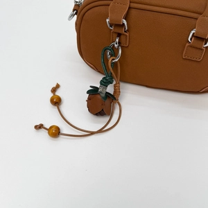 Detailed close-up of brown leather rose charm with green leaves and wooden beads on a handbag