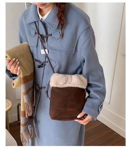 Detail of a brown suede bucket bag with plush faux fur trim and embroidered logo