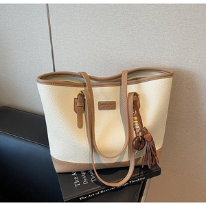 Close-up of cream pebble leather tote bag with brown trim and tassel detail
