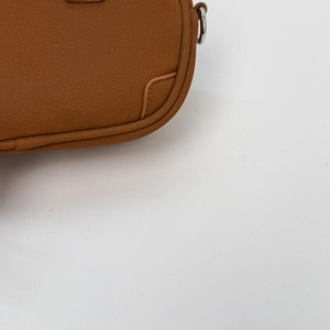 Detailed view of brown crossbody bag showing fine stitching and silver D-ring buckle
