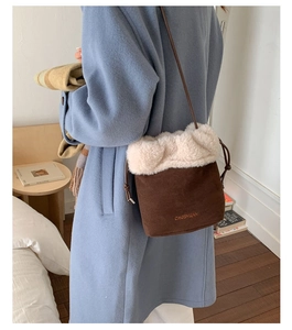 Brown suede drawstring bucket bag with faux fur trim shown on model in bedroom