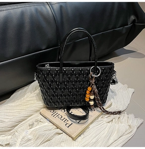 Detailaufnahme der schwarzen geflochtenen Eimertasche mit Holzperlen und Magazin
