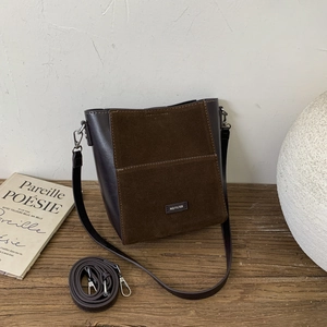 Detail of retro brown patchwork bucket bag with NO FILTER logo and leather texture