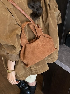 Brown frosted suede bucket bag with top handle and crossbody strap in a fashion outfit style