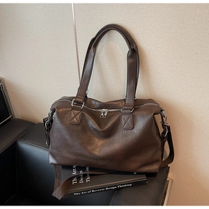 Macro shot of dark brown faux leather travel bag with dual zippers and silver hardware