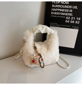 Dettaglio della borsa di peluche bianca con manico in pelle arricciata e ciondolo marrone