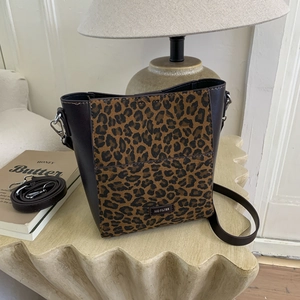 Detail of leopard print bucket bag with NO FILTER badge and adjustable leather strap