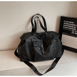 Close-up of black nylon travel bag with adjustable strap and large front buckle pocket
