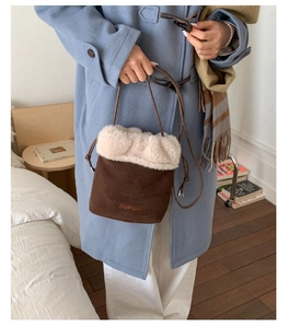 Detailed view of the brown suede bucket bag with cream faux fur trim and embroidery