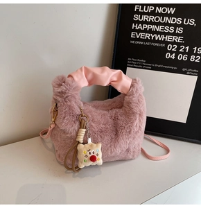 Dettaglio borsa rosa in peluche con manico arricciato e ciondolo a forma di pupazzo