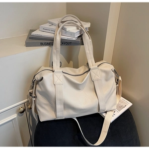 Detailed macro of cream faux leather travel bag showing lychee grain and reinforced stitching