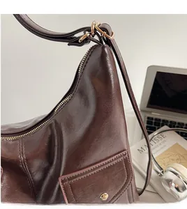 Detail of dark brown leather shoulder bag with gold zipper and stylish long strap