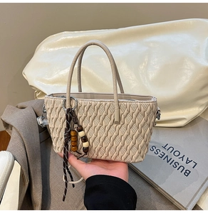 Detailansicht der beigefarbenen Handtasche mit Webstruktur und dekorativen Holzperlen