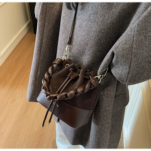Detail of dark brown leather bucket bag with braided handle and drawstring closure