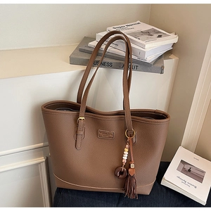 Detail of dark brown pebble leather tote bag with vintage bead and tassel charm