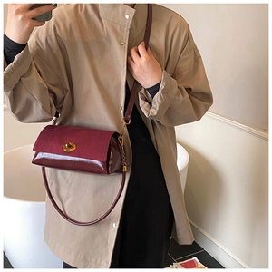 Détail du sac bordeaux foncé présentant des textures de patchwork en cuir verni et mat