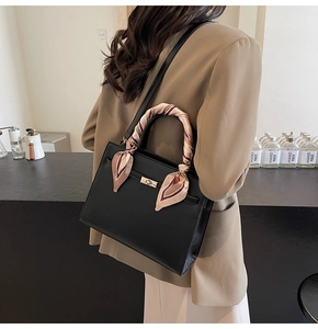 Détail d'un sac à main noir brillant avec poignée en soie et fermoir rotatif