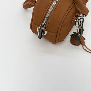 Detail of caramel faux leather bag with lychee texture and strawberry charm