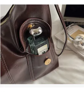 Detail view of the side magnetic pocket on dark brown leather shoulder bag with storage