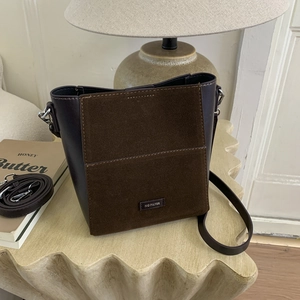 Detail of vintage brown bucket bag with matte suede texture and adjustable strap
