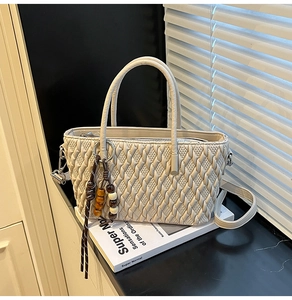 Detailansicht der cremefarbenen Stepptasche mit Webmuster, Holzperlen-Anhänger und Verschluss