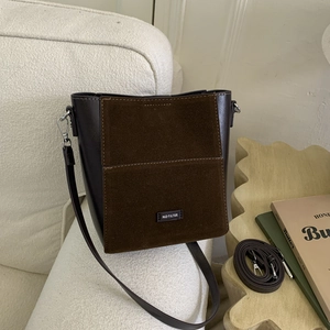 Detail of dark brown leather bucket bag with matte suede texture and NO FILTER lettering