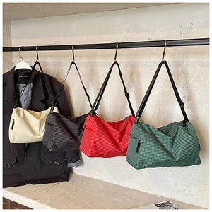Detail of four plaid crossbody bags in cream, grey, red and green with adjustable straps