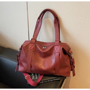 Detail of dark red lychee grain PU leather travel bag with reinforced square stitching