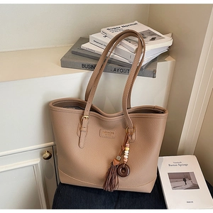 Close-up of brown pebbled leather tote bag with elegant tassel and bead charm
