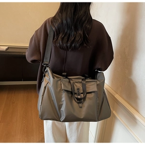 Detailed view of deep grey waterproof nylon travel bag shown on a model for size reference