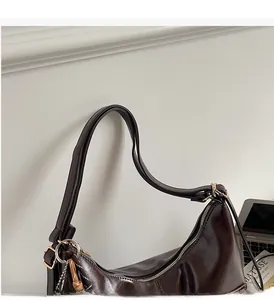 Detail view of reinforced shoulder straps on dark brown glossy leather tote bag
