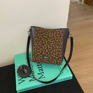 Detail of leopard print bucket bag with brown leather panels and No Filter label
