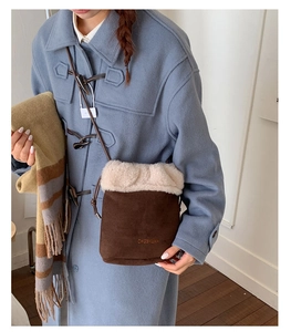 Detail of vintage suede shoulder bucket bag with white faux fur trim and debossed letters