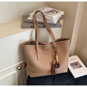 Detail of dark brown leather tote bag showing lychee grain texture and tassel charm