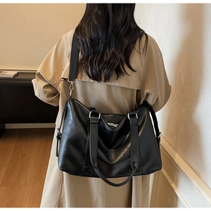 Detailed view of a black tote bag with silver hardware and adjustable wide fabric strap