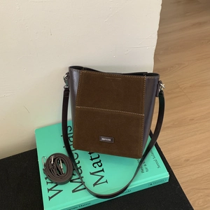Macro detail of brown leather bucket bag with NO FILTER label on the suede front pocket