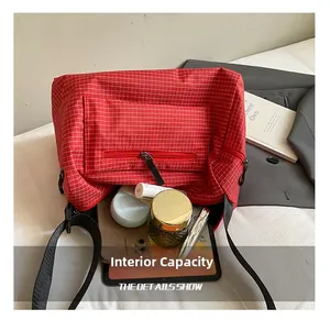 Macro detail showing the large interior capacity of the red checkered crossbody bag
