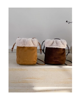 Detail of drawstring bucket bags with plush faux fur trim and suede fabric in warm colors