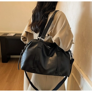Detail of black faux leather travel tote bag with reinforced straps and zipper closure