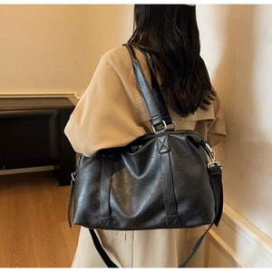 Close-up of black PU leather travel bag showing matte texture and adjustable strap