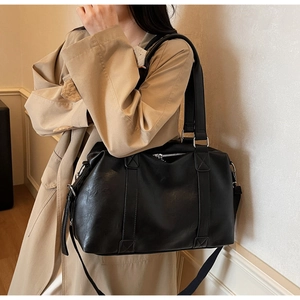 Close-up of black PU leather tote bag with thick handles and adjustable strap details