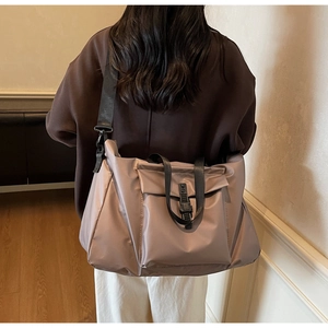 Detail of a large pink nylon travel bag with shoulder strap worn by a female model