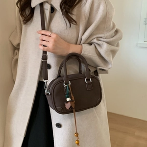Detail of dark brown Boston bag with leather flower charm and wooden beads tassel