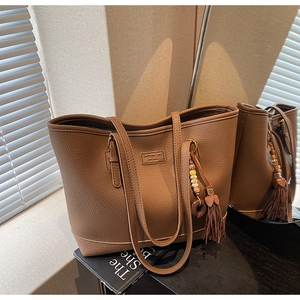 Detailed view of brown lychee texture tote bag with bohemian beaded tassel charm