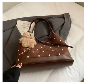 Close-up of vintage brown polka dot tote bag with plush bunny charm and leather detail