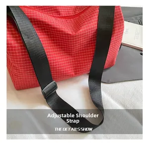 Detail of red plaid crossbody bag with adjustable wide black nylon shoulder strap