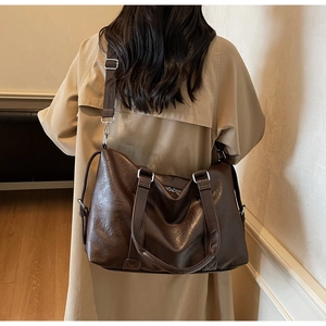 Detail of a large dark brown tote bag on a trench coat with a wide fabric strap