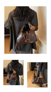 Detail of dark brown vintage faux-leather shoulder bag with pocket and plush bear charm